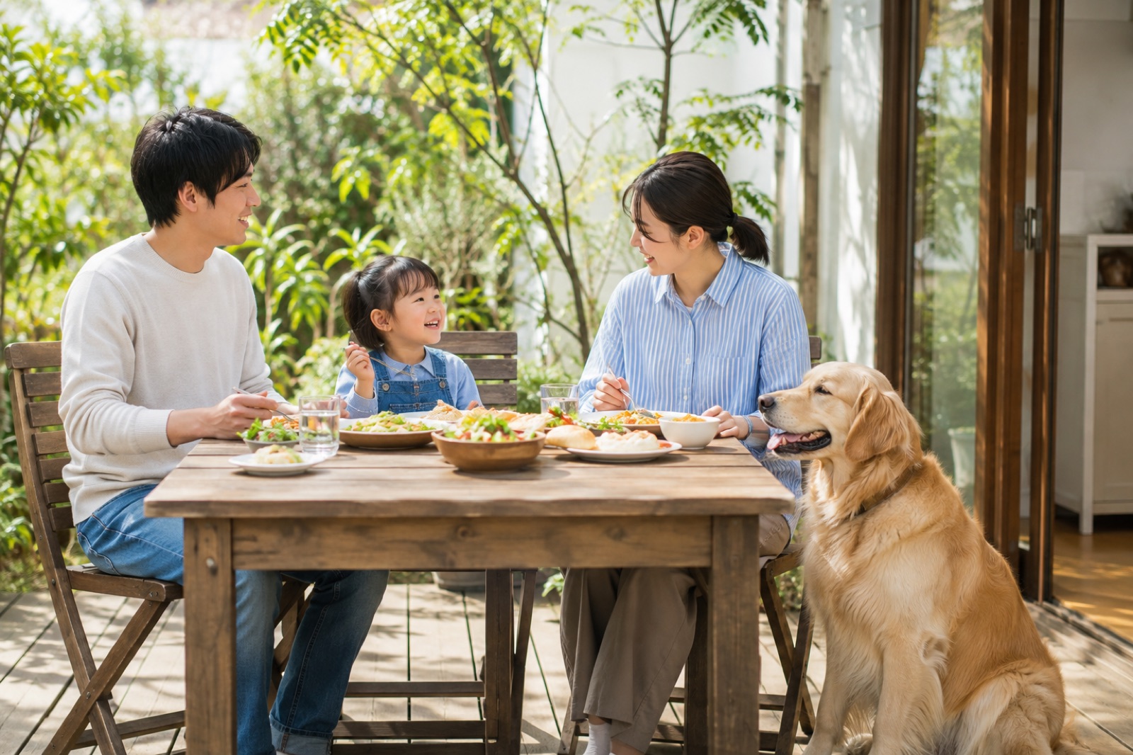 テラス席で愛犬と一緒にランチを食べる家族